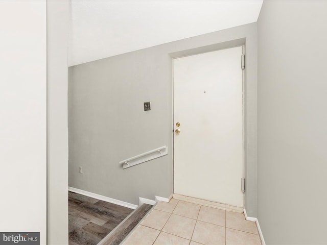 doorway with light tile patterned flooring and baseboards