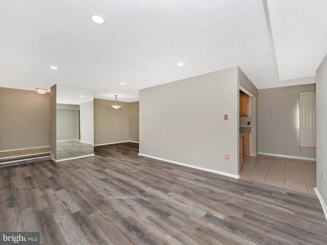 unfurnished room featuring a textured ceiling, dark wood-style flooring, recessed lighting, and baseboards