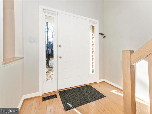 foyer entrance featuring visible vents, baseboards, and wood finished floors