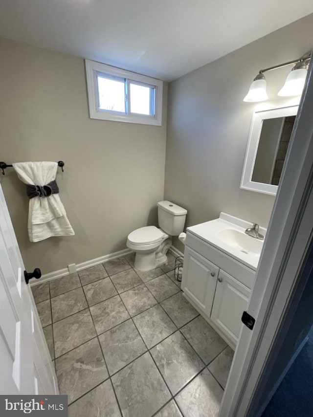 bathroom with toilet, tile patterned floors, baseboards, and vanity