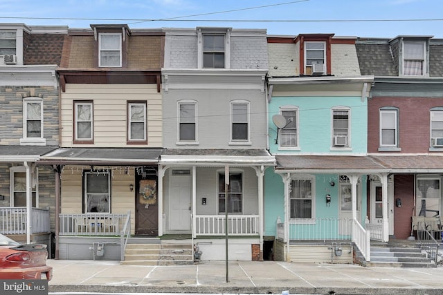 townhome / multi-family property featuring a shingled roof, covered porch, and mansard roof