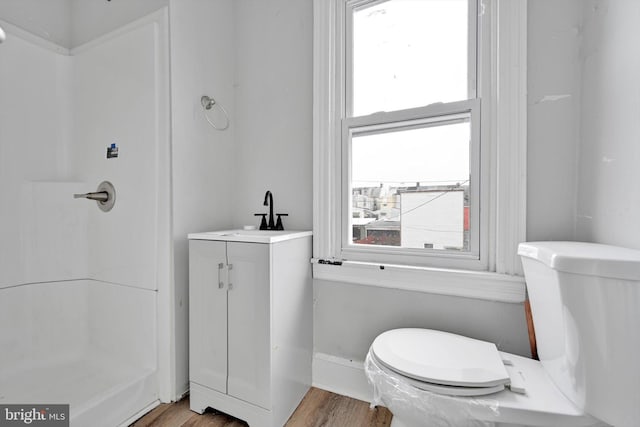 full bathroom with toilet, walk in shower, a sink, and wood finished floors