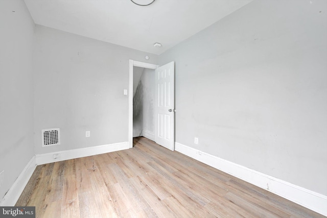 spare room featuring light wood-style floors, visible vents, and baseboards