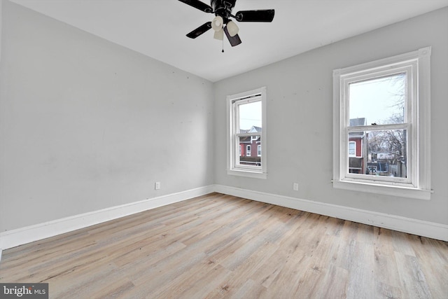 spare room with light wood finished floors, a ceiling fan, and baseboards