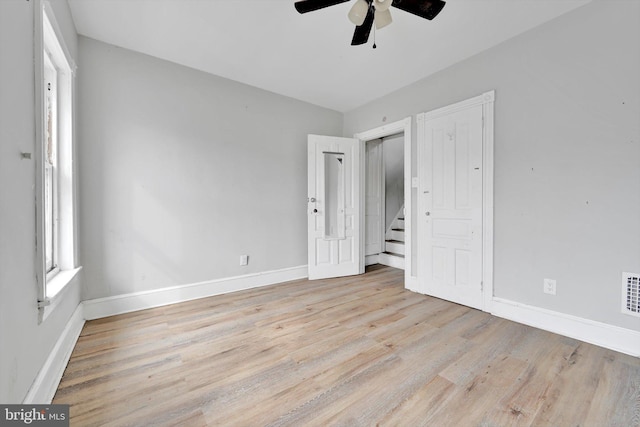 unfurnished bedroom featuring a ceiling fan, baseboards, visible vents, and light wood finished floors