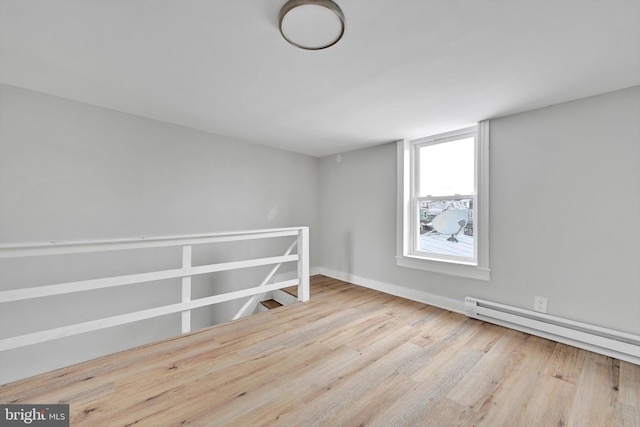 spare room featuring baseboards, baseboard heating, and light wood-style floors