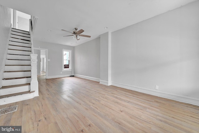 unfurnished living room with light wood finished floors, visible vents, ceiling fan, baseboards, and stairs