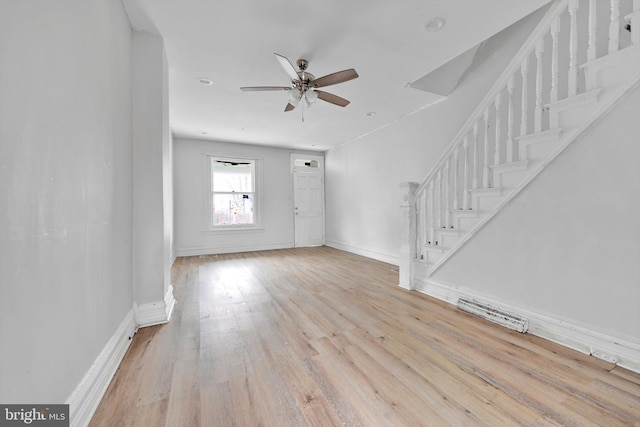 interior space featuring ceiling fan, light wood-style flooring, visible vents, baseboards, and stairs