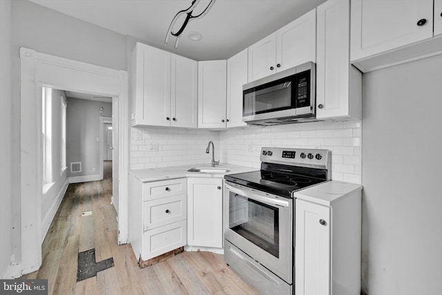 kitchen with stainless steel appliances, white cabinets, light countertops, and backsplash