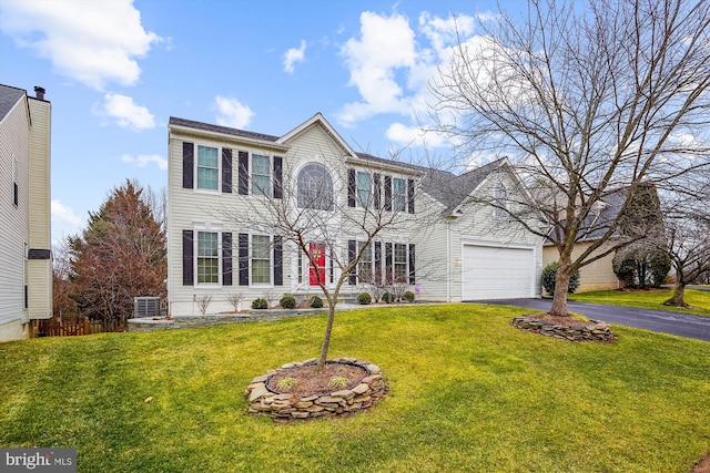 colonial home with driveway, a front yard, and cooling unit