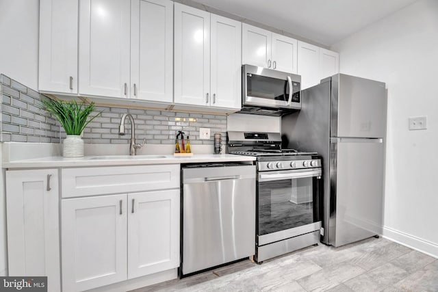 kitchen featuring stainless steel appliances, a sink, white cabinets, light countertops, and tasteful backsplash