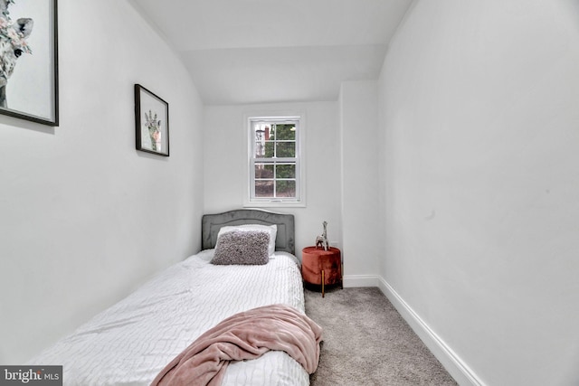 carpeted bedroom with lofted ceiling and baseboards