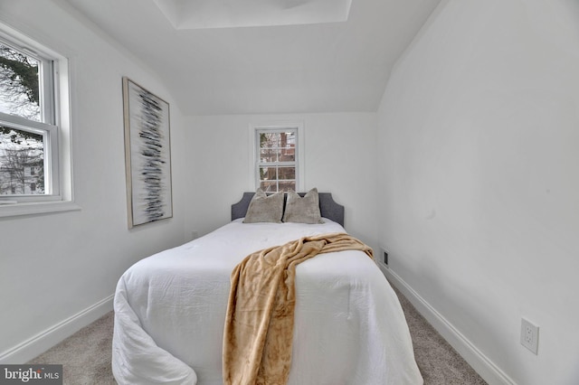 bedroom featuring light colored carpet, vaulted ceiling, and baseboards