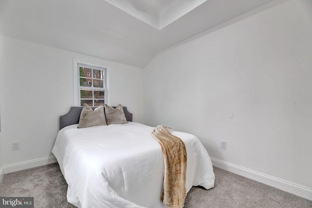 bedroom featuring light colored carpet, vaulted ceiling, and baseboards