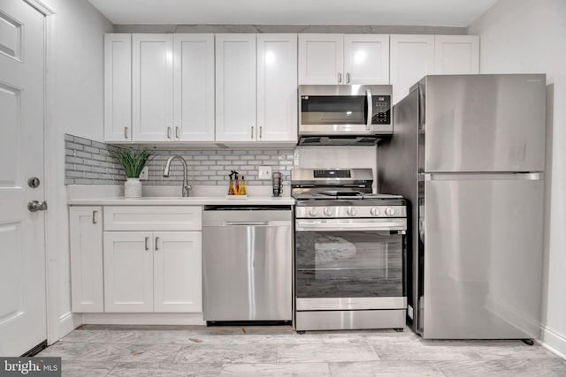 kitchen featuring stainless steel appliances, decorative backsplash, light countertops, and white cabinets