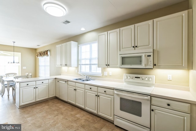 kitchen with a peninsula, white appliances, visible vents, light countertops, and decorative light fixtures