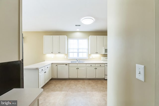 kitchen featuring white appliances, visible vents, white cabinets, light countertops, and a sink