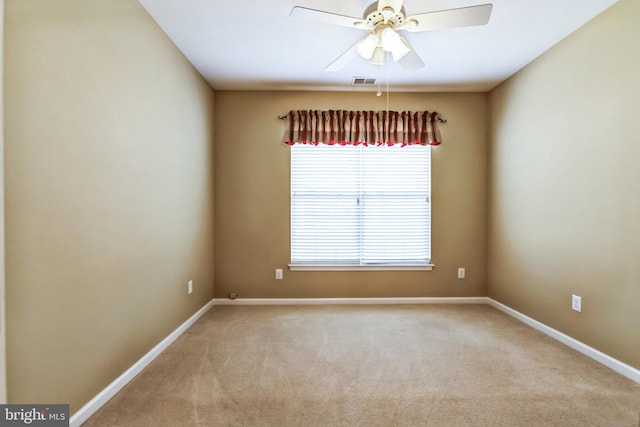 spare room with baseboards, visible vents, a ceiling fan, and light colored carpet