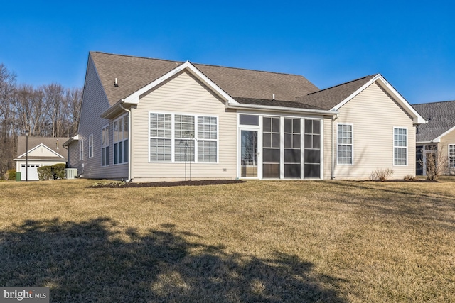 rear view of property featuring a shingled roof, a sunroom, and a yard