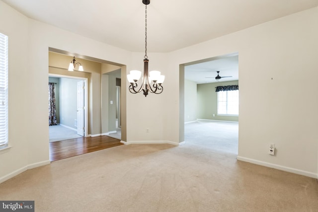 spare room featuring a notable chandelier, baseboards, and carpet flooring