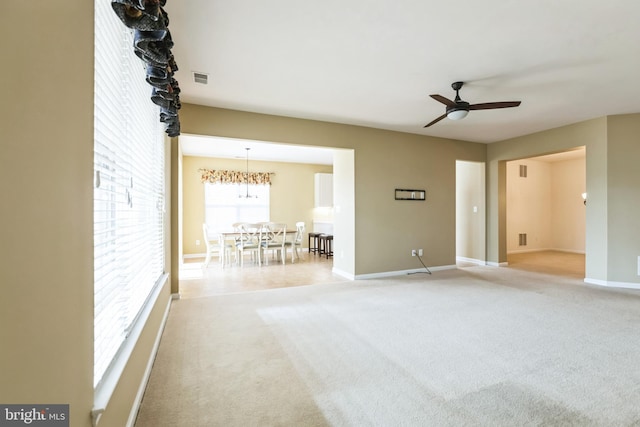 empty room with ceiling fan, visible vents, baseboards, and light colored carpet