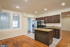 kitchen featuring recessed lighting, stainless steel appliances, dark brown cabinets, light wood-type flooring, and a center island