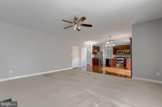 unfurnished living room featuring ceiling fan, light colored carpet, and baseboards