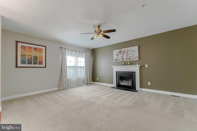 unfurnished living room featuring light carpet, a fireplace with flush hearth, baseboards, and a ceiling fan