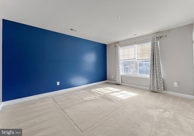 spare room with light colored carpet, visible vents, and baseboards