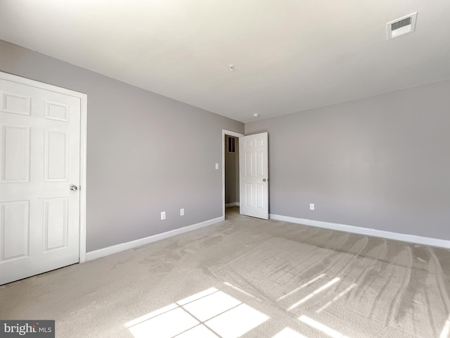 empty room featuring light carpet, visible vents, and baseboards