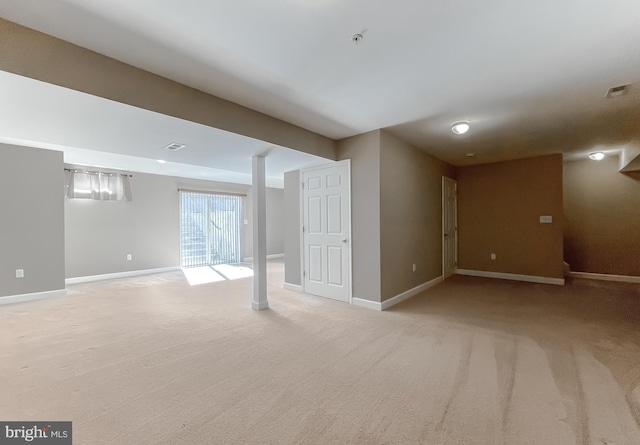 below grade area with light colored carpet, visible vents, and baseboards