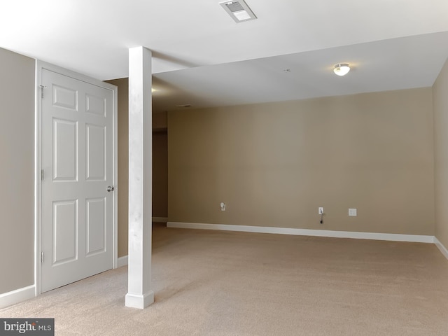 basement featuring baseboards, visible vents, and light colored carpet