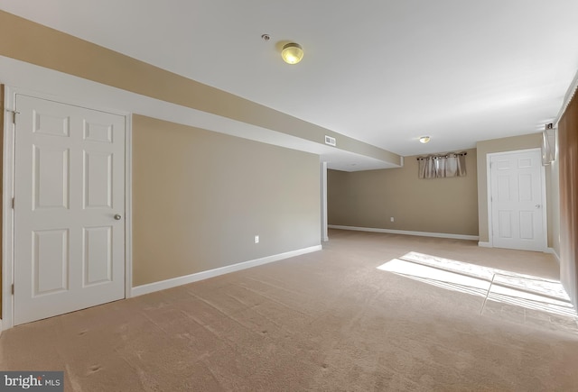 finished basement featuring baseboards, visible vents, and light colored carpet