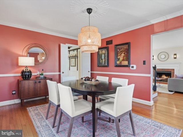 dining room featuring visible vents, crown molding, baseboards, a fireplace, and hardwood / wood-style flooring