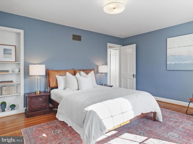 bedroom with visible vents, baseboards, and wood finished floors