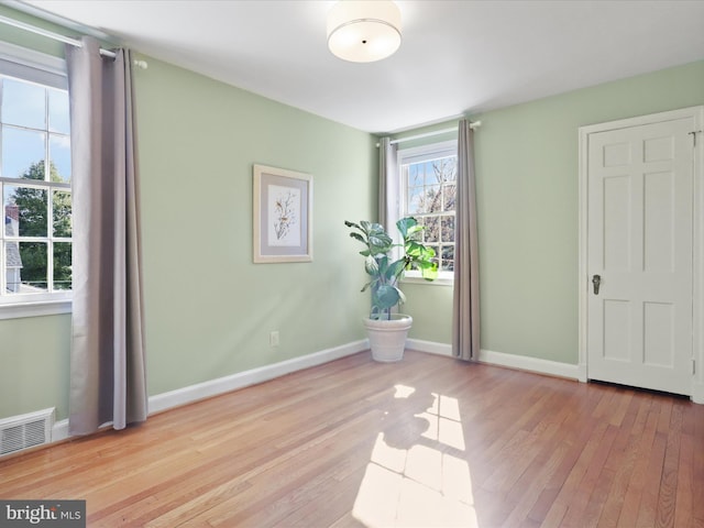 unfurnished room featuring visible vents, baseboards, and wood finished floors