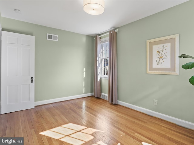 unfurnished room featuring visible vents, baseboards, and hardwood / wood-style flooring