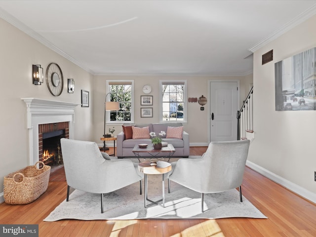 living room with ornamental molding, hardwood / wood-style flooring, a fireplace, baseboards, and stairs