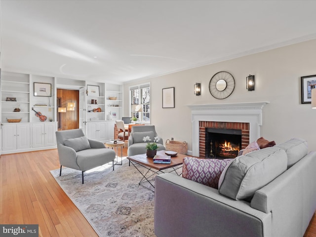 living area with built in features, light wood-style flooring, and a fireplace