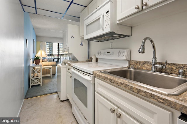 kitchen with white appliances, white cabinets, and a sink