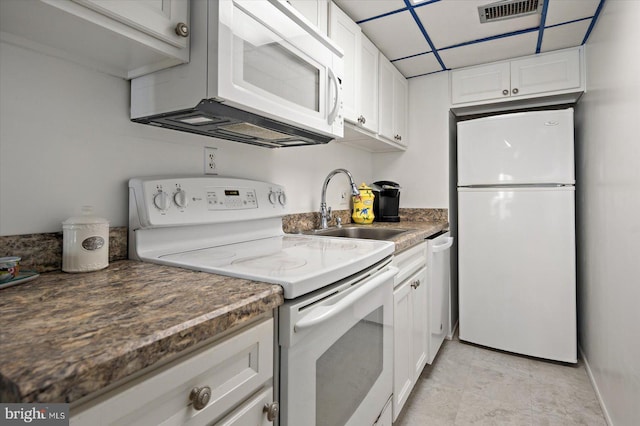 kitchen with white appliances, visible vents, a sink, and white cabinets