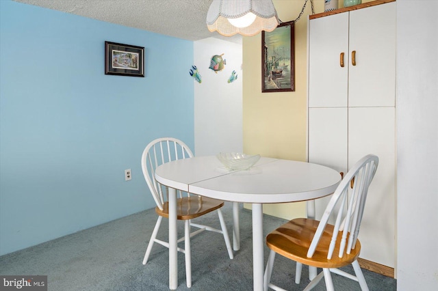 carpeted dining room with a textured ceiling