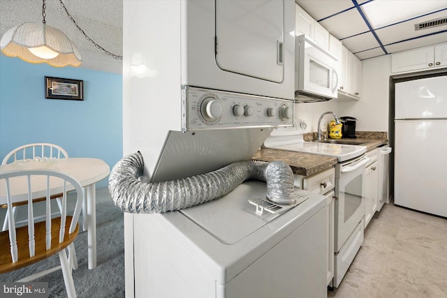 washroom with stacked washer / drying machine, laundry area, visible vents, and a sink