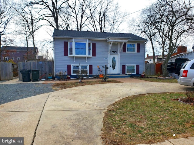 split foyer home with a front yard, concrete driveway, and fence