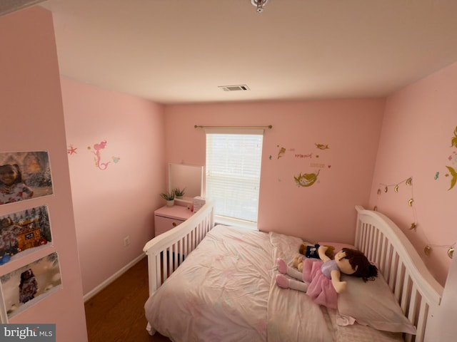 bedroom with baseboards, visible vents, and wood finished floors