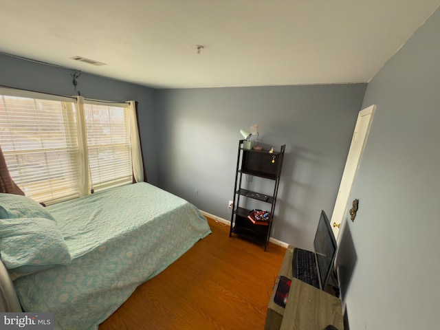 bedroom featuring visible vents, baseboards, and wood finished floors