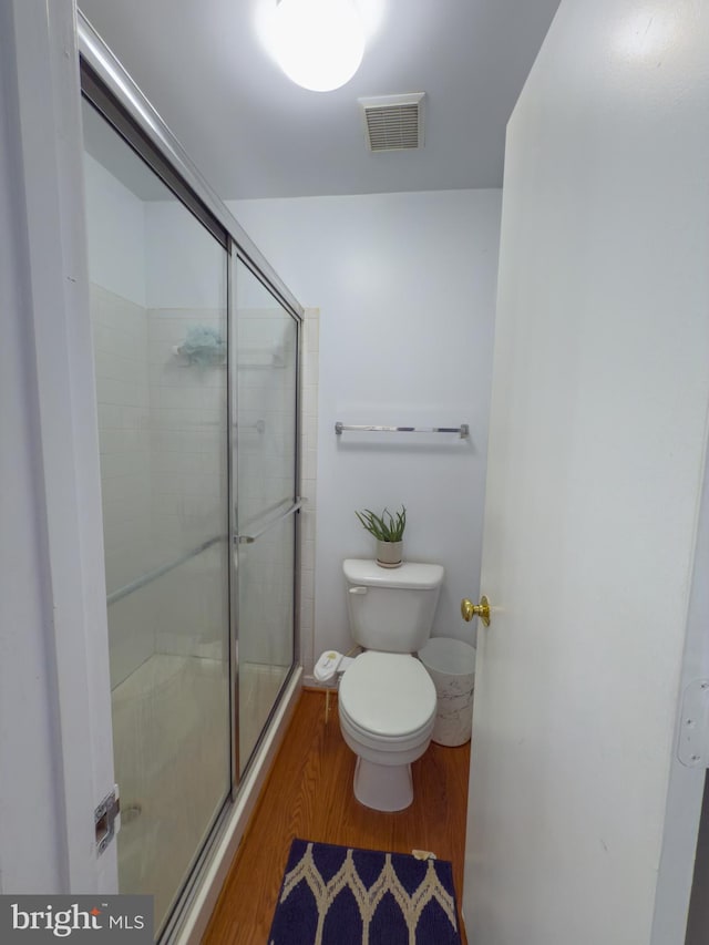 full bathroom with toilet, a shower stall, visible vents, and wood finished floors