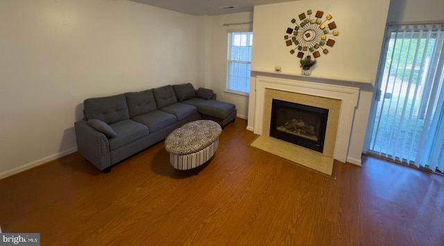 living room featuring a fireplace with flush hearth, baseboards, and wood finished floors