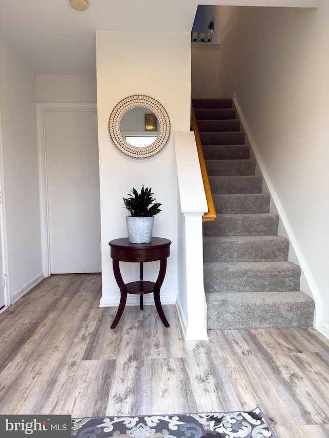 staircase with baseboards and wood finished floors