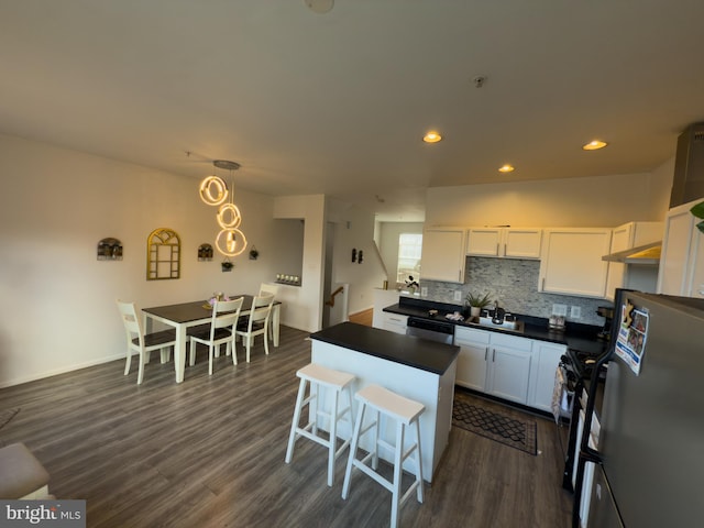 kitchen featuring white cabinets, backsplash, freestanding refrigerator, dishwasher, and dark countertops